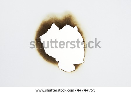 close up of burnt paper hole on white background