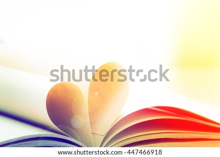 Pages of open book rolled in heart shape with color filters
