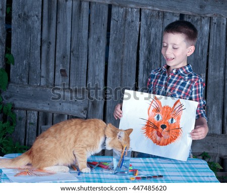 Happy little boy with a picture of a cat, which he painted.Cat sits next