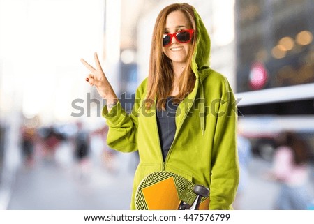 Young girl doing victory gesture on unfocused background