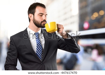 Young businessman drinking a coffee over unfocused background