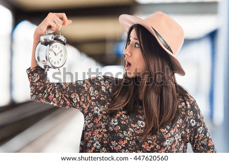 Surprised woman holding vintage clock on unfocused background