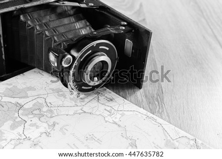 Old photo camera and paper map. Black and white photo