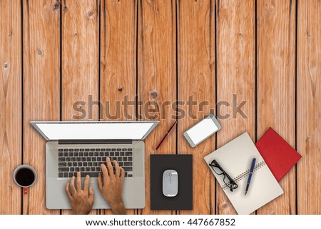A man is working by using a laptop computer on vintage wooden table. Hands typing on a keyboard. Top view.
