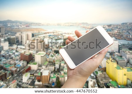 Hand holding smartphone with city background