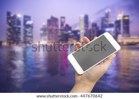 Hand holding smartphone with city background