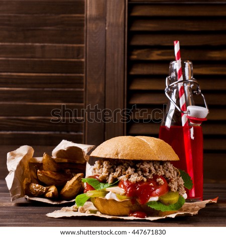 Burger with minced meat and vegetables on a wooden background. Selective focus.