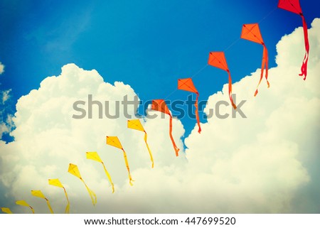 Ribbon is of multi-colored flags against the blue of the cloudy sky or kites