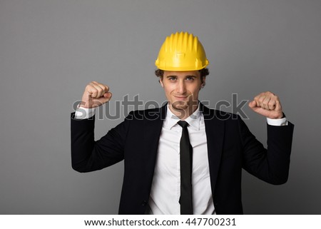 elegant man in suit with yellow protection helmet on gray background with empty space