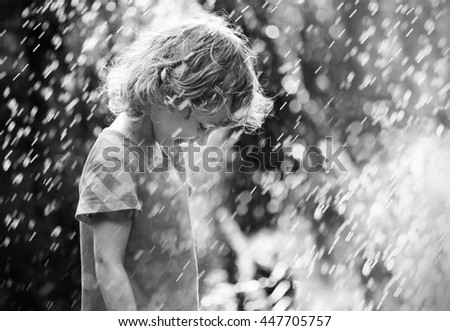 Photo of happy little girl standing under summer rain. Black and white
