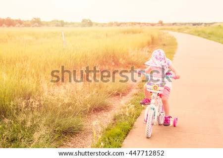 Toddler learning how to ride bicycle on the trail.