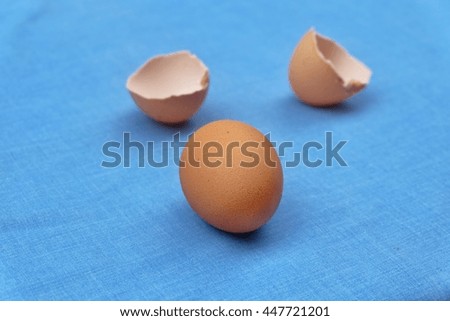 
Egg and shell on blue fabric background.