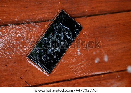 modern smartphone waterproof drop of water and wood background.