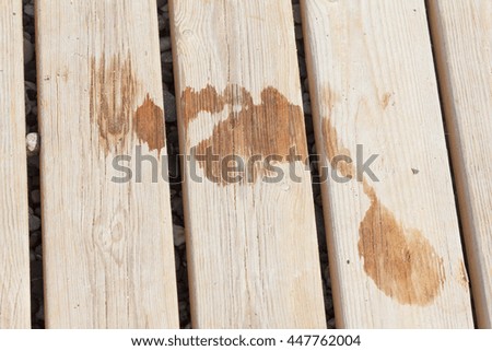 Wet footprint on wood plank on the beach