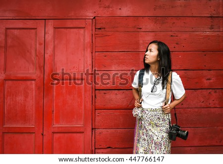 Portrait beautiful asia women with camera and sunglasses on red wooden door background.