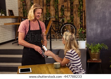 Woman paying with mobile payment in the cafe