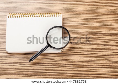 notebook and magnifying glass.research idea