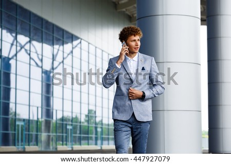 Picture of confident handsome young redhaired businessman  talking on phone