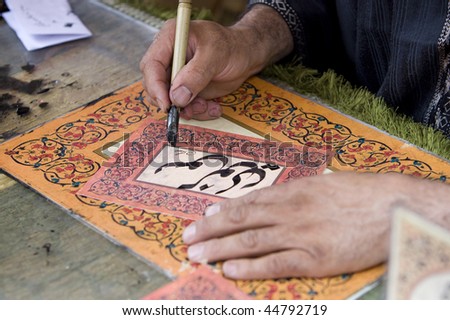 a man writing a name with traditional arab characters in a beautiful card