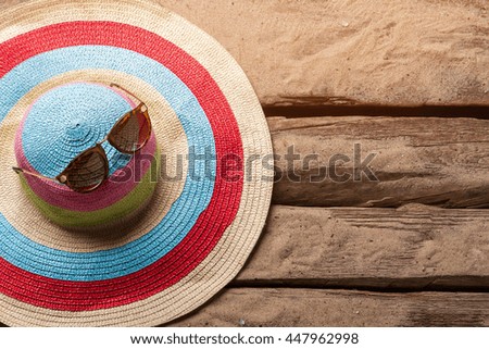 Beach hat and sunglasses. Red and blue striped hat. It's time for sunbathing. Warmth of tropical sun.