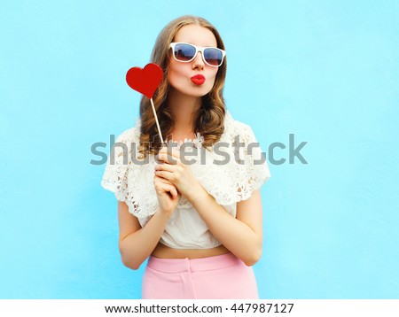 Portrait pretty woman and red lollipop over colorful blue background