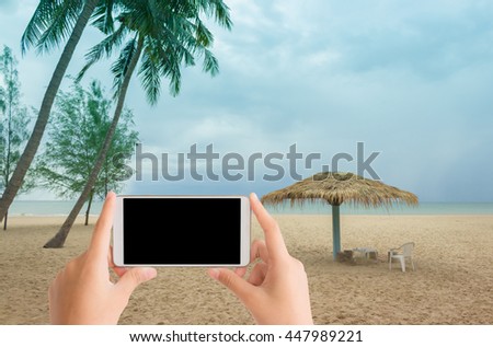 woman use mobile phone and the beach with a straw umbrella in the cloudy day