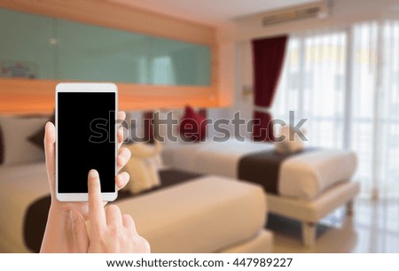 woman use mobile phone and blurred image of double bed room in the hotel