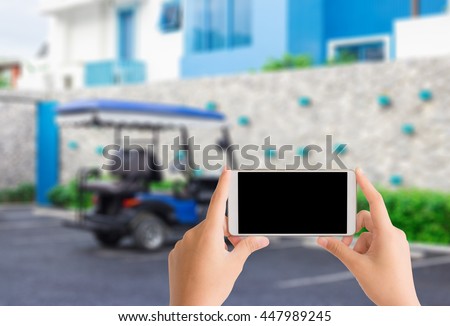 woman use mobile phone and blurred image of blue golf cart park in the car park near blue hotel
