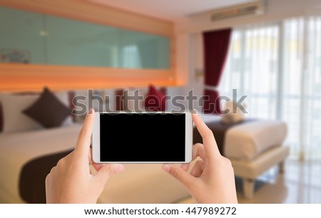 woman use mobile phone and blurred image of double bed room in the hotel