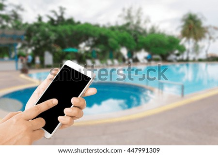 woman use mobile phone and blurred image of swimming pool in the hotel