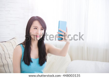 young woman is taking selfies in living room at home, asian