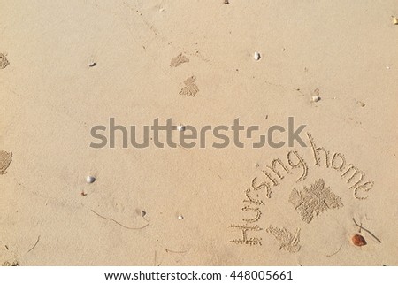 written words "Hursing home" on sand of beach