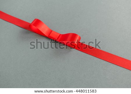 Red ribbon and bow with soft shadow on gray background