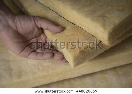 Hand holding a fiberglass batt. Image of home insulation. Royalty-Free Stock Photo #448020859