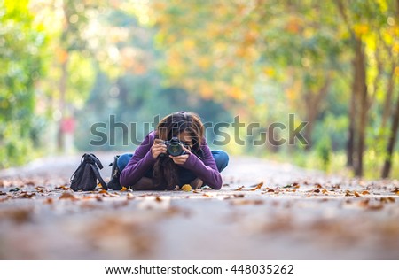 woman with DSLR camera take photo in a beautiful park with wonderful atmosphere of trees and leaves