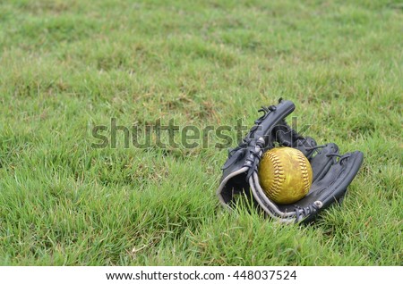 old softball in old glove on field grass.field softball have lawn.