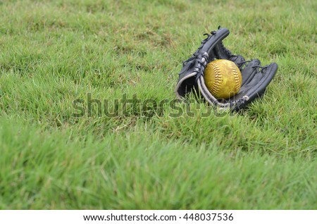 old softball in old glove on field grass.field softball have lawn.