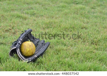 old sofball in old glove softball. glove softball on grass. 