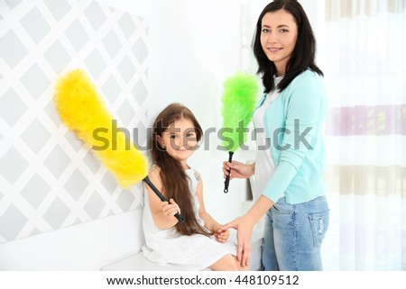 Daughter and mother cleaning dust in room