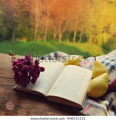 Book and pears on the table in the autumn park.