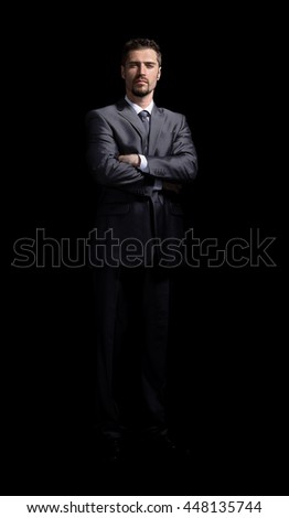 Handsome business man posing in grey suit on dark background in studio.