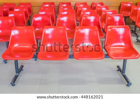 Rows of an empty plastic seats at hospital with red.