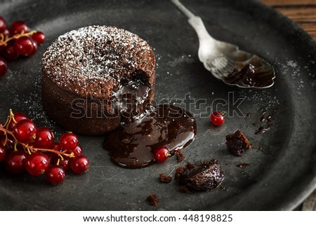 Warm Chocolate Lava Cake with Bite Taken Out of Molten Center and Red Currants on Vintage Metal Plate Royalty-Free Stock Photo #448198825