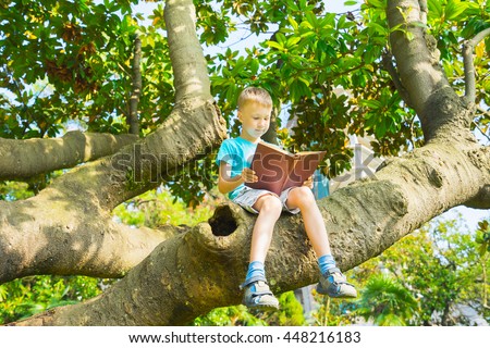 Little boy sitting on  big tree and reading book.