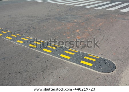 Traffic safety speed bump with crosswalk on an asphalt road. Speed bumps (or speed breakers) are the common name for a family of traffic calming devices.