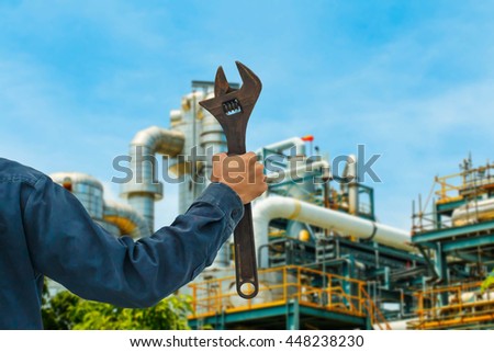 Hands holding a large wrench industrial background.