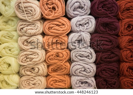 Stacks of colorful knitting wool balls arranged on shelf - background