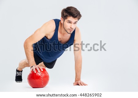 Full length portrait of a sports man workout with fitness ball isolated on a gray background