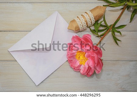 Envelope, gift and flower on a light wooden background