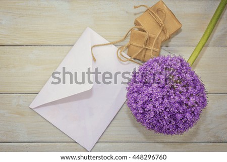 Envelope, gift and flower on a light wooden background